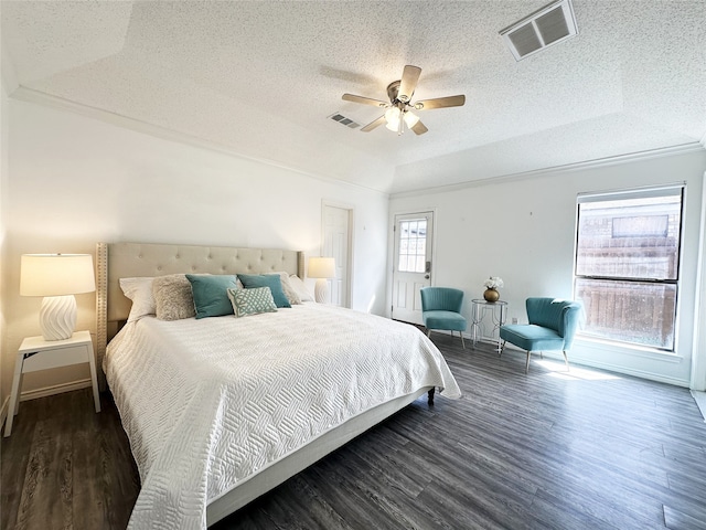 bedroom featuring visible vents, a raised ceiling, a textured ceiling, and wood finished floors