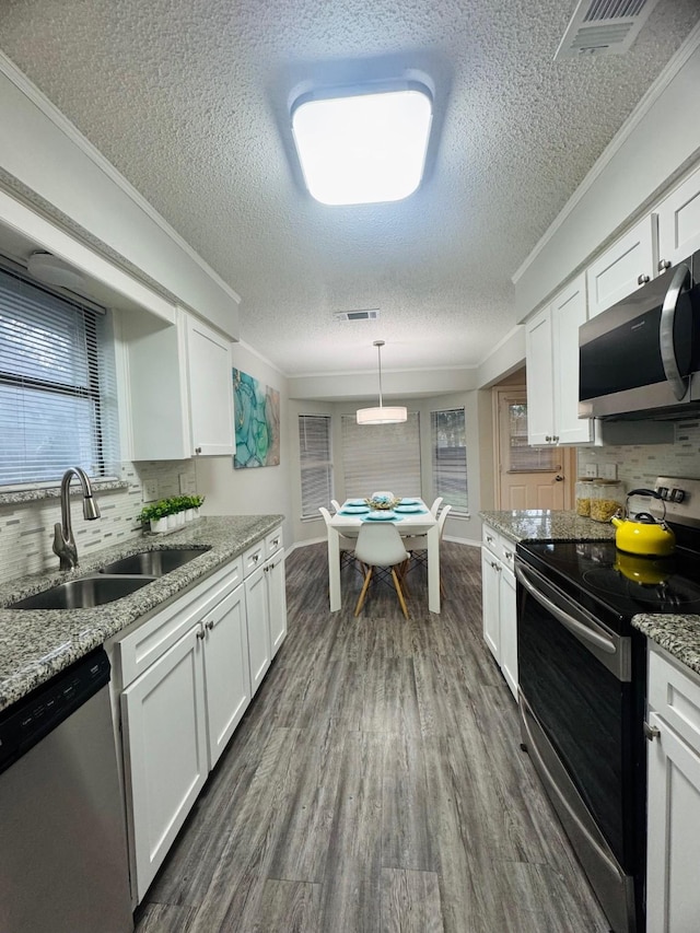 6503 Tempest Dr, Arlington, TX 76001 - kitchen featuring stainless steel appliances, a textured ceiling, white cabinetry, a sink, and decorative backsplash