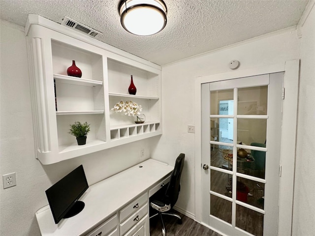 home office featuring built in study area, a textured ceiling, wood finished floors, and visible vents