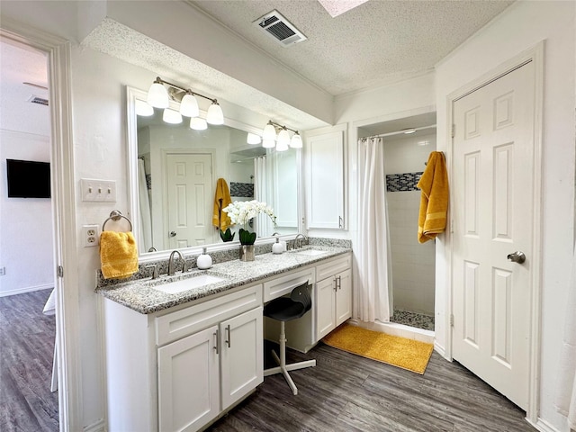 full bath with visible vents, a sink, a textured ceiling, and a stall shower