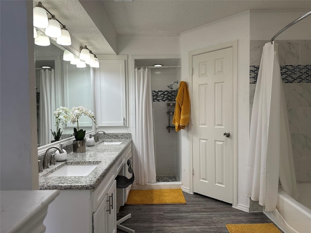 full bath with a sink, double vanity, a textured ceiling, and wood finished floors