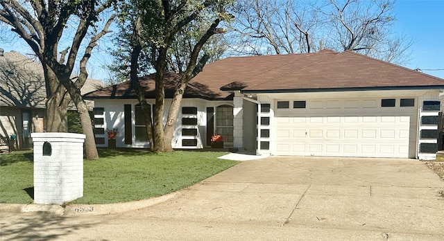 ranch-style house featuring concrete driveway, a front lawn, roof with shingles, and an attached garage