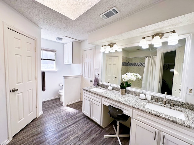 bathroom with visible vents, a sink, a textured ceiling, and wood finished floors