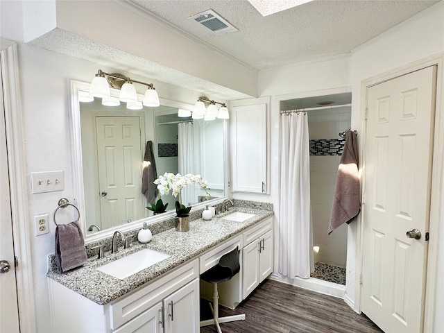 full bath with a textured ceiling, visible vents, a sink, and wood finished floors