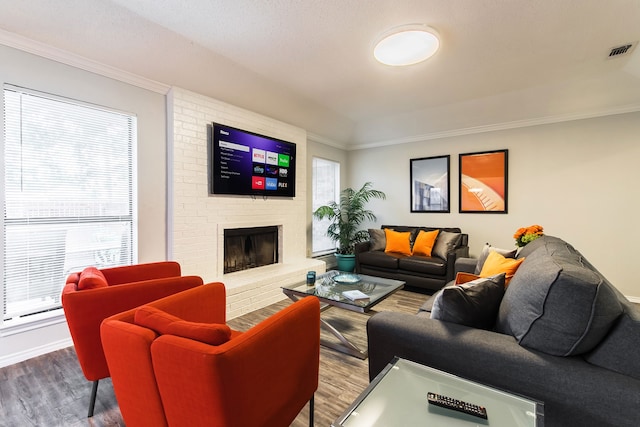 living room with a fireplace, wood finished floors, visible vents, and crown molding