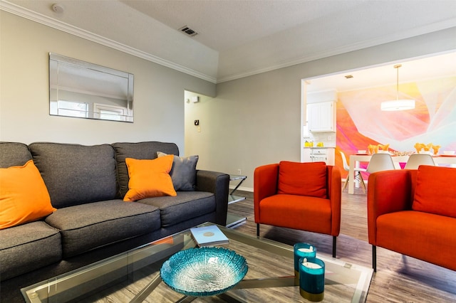 living room featuring ornamental molding, wood finished floors, visible vents, and baseboards