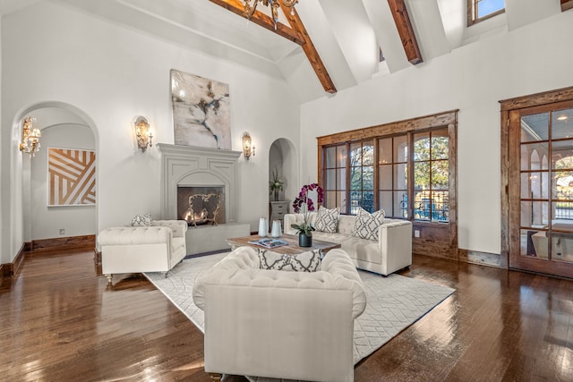 living area featuring high vaulted ceiling, beam ceiling, arched walkways, a lit fireplace, and wood-type flooring