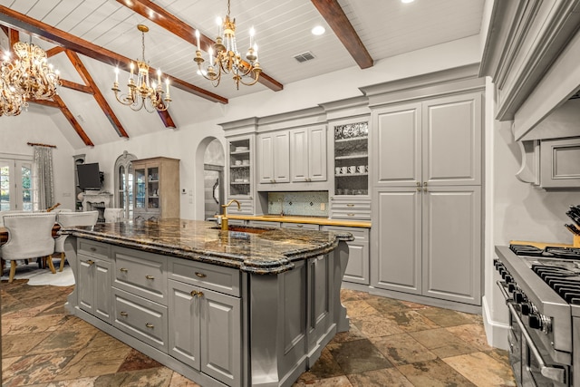 kitchen with stone tile flooring, tasteful backsplash, gray cabinetry, and a chandelier