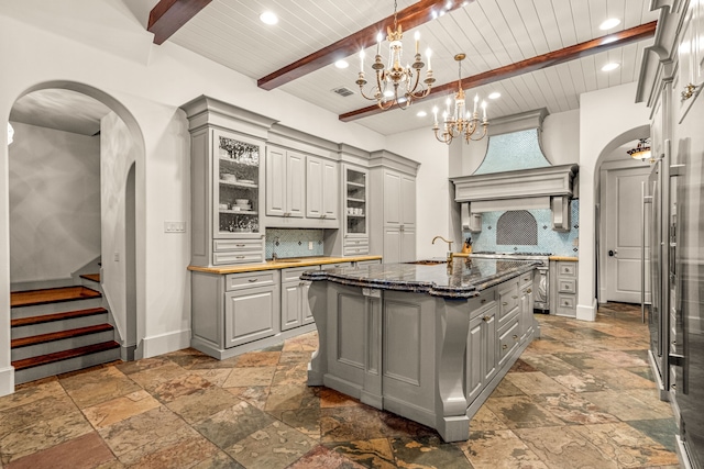 kitchen featuring arched walkways, gray cabinets, and backsplash