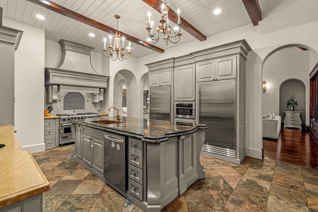 kitchen featuring arched walkways, gray cabinets, high quality appliances, and a sink