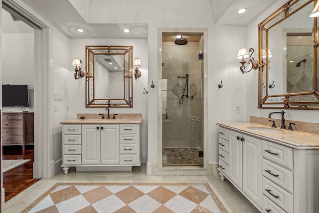 full bath with a stall shower, two vanities, baseboards, and a sink