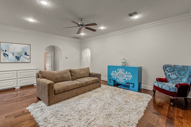 living room featuring a ceiling fan, dark wood-style floors, visible vents, arched walkways, and ornamental molding