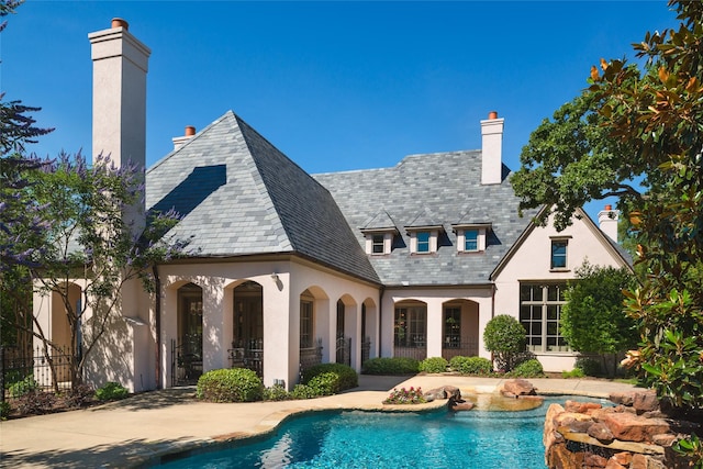 back of house featuring an outdoor pool, a high end roof, and a chimney