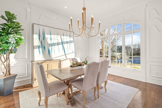 dining area featuring a decorative wall, ornamental molding, an inviting chandelier, and wood finished floors