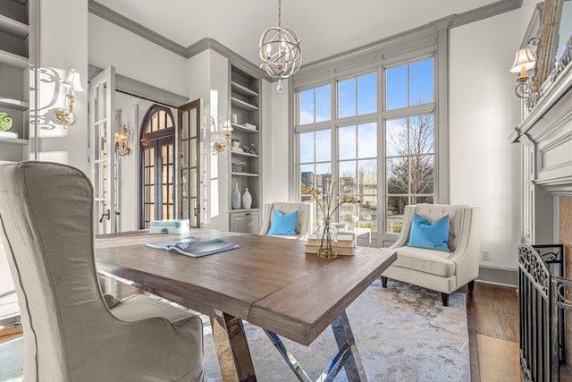 office area featuring built in shelves, a notable chandelier, wood finished floors, crown molding, and baseboards