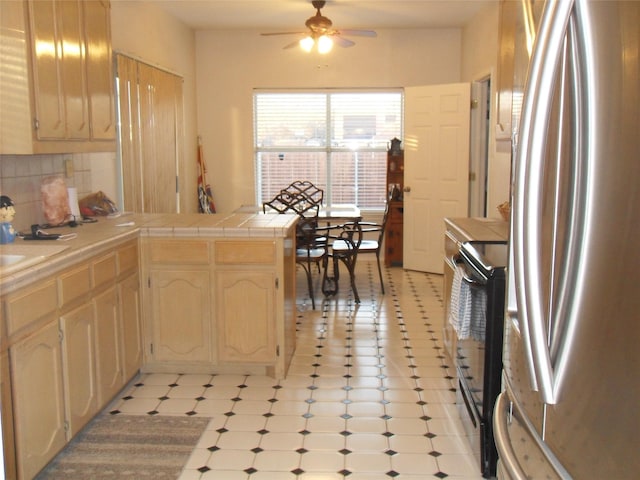 kitchen with black range with electric cooktop, a peninsula, backsplash, freestanding refrigerator, and tile counters