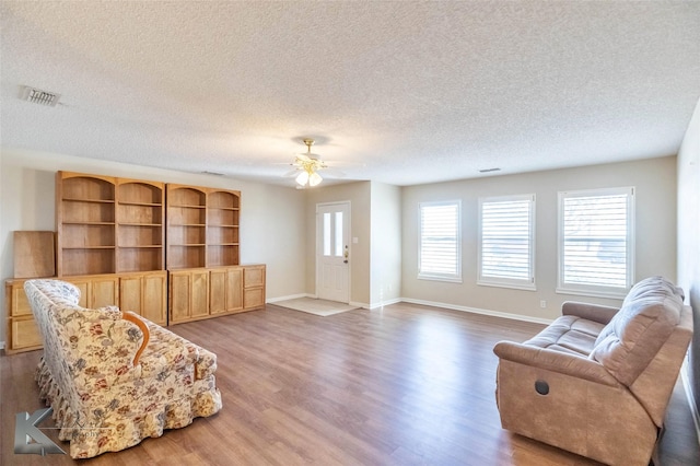 living room with baseboards, visible vents, and wood finished floors