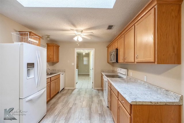 kitchen featuring white appliances, visible vents, light wood-style floors, a ceiling fan, and light countertops