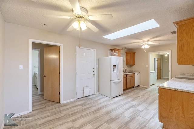 kitchen with white appliances, a skylight, baseboards, a ceiling fan, and a textured ceiling