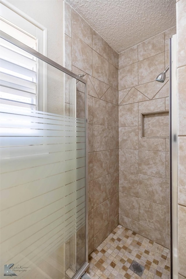 bathroom with a shower stall and a textured ceiling