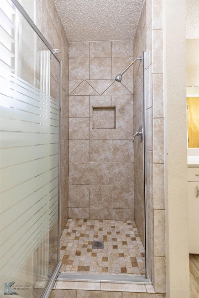 full bathroom featuring a textured ceiling and a stall shower