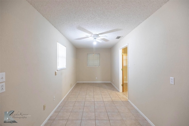 unfurnished room with light tile patterned floors, ceiling fan, a textured ceiling, visible vents, and baseboards