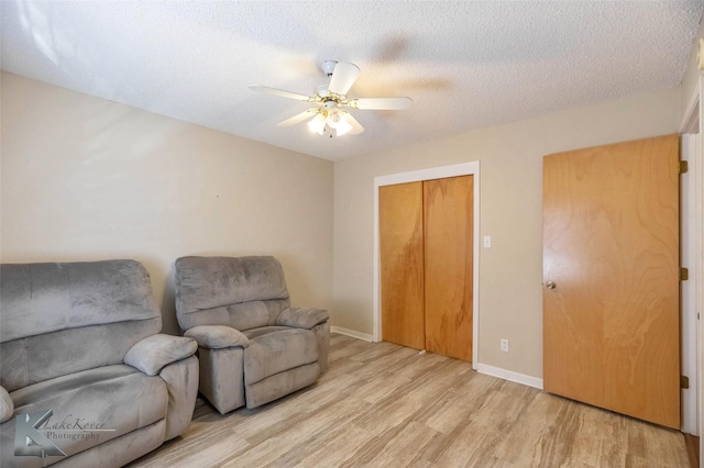 sitting room featuring baseboards, ceiling fan, a textured ceiling, and light wood finished floors