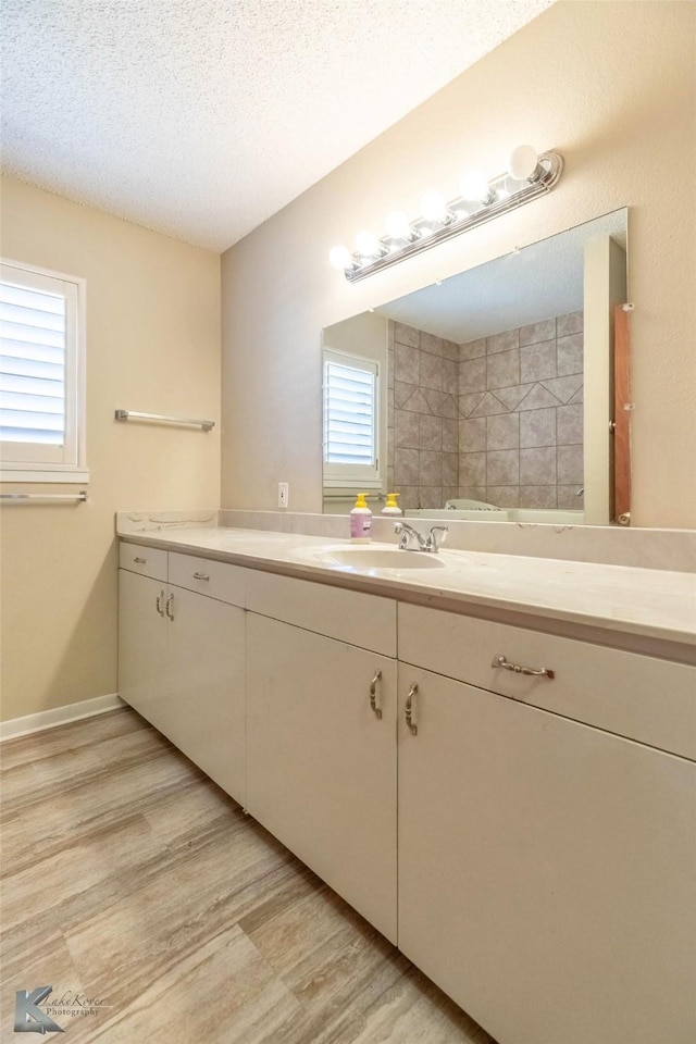 bathroom with a textured ceiling, vanity, and wood finished floors