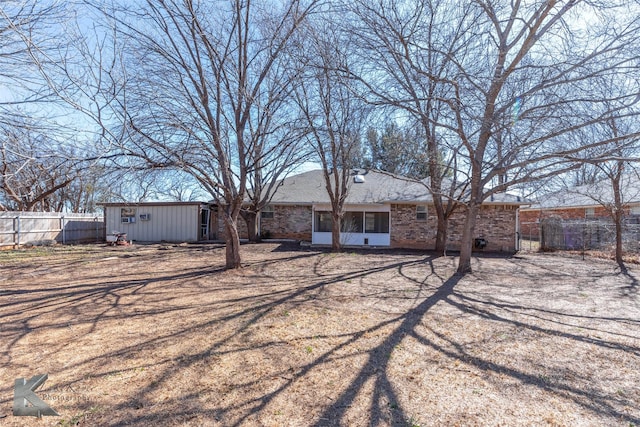 rear view of property featuring brick siding and fence