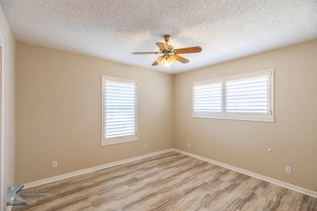 empty room featuring a ceiling fan, light wood-type flooring, a textured ceiling, and baseboards