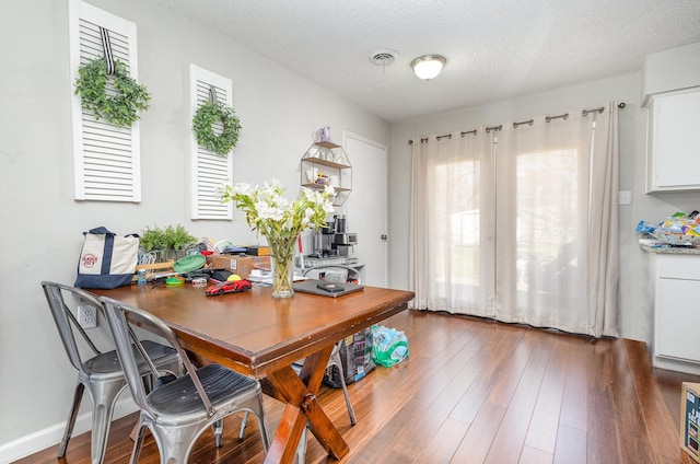 dining area with visible vents, a textured ceiling, baseboards, and wood finished floors