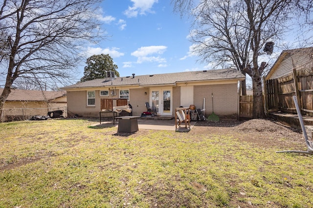 rear view of property with brick siding, fence, a patio, and a lawn