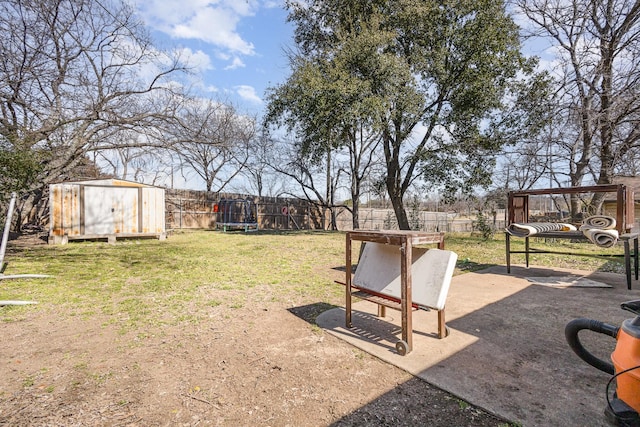 view of yard featuring a storage unit, a trampoline, an outdoor structure, and a fenced backyard