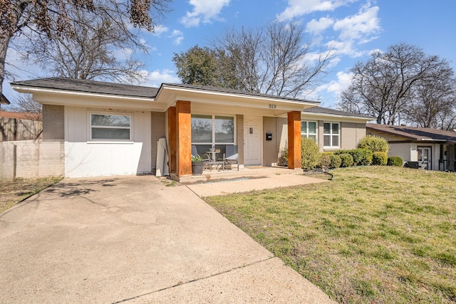 single story home with covered porch, driveway, brick siding, and a front yard