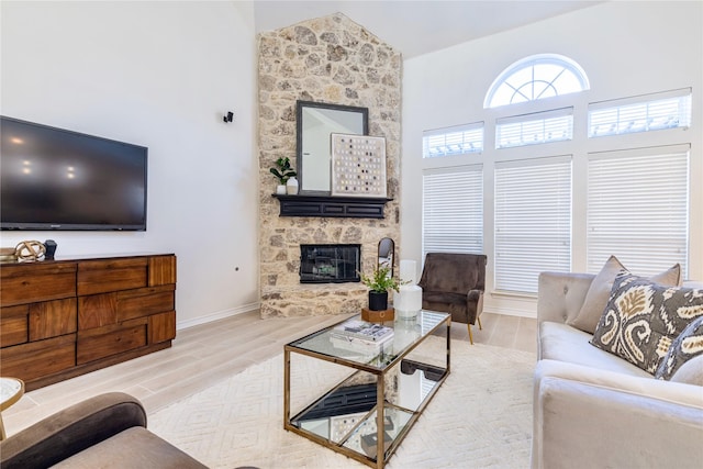 living room featuring wood finished floors, a fireplace, high vaulted ceiling, and baseboards
