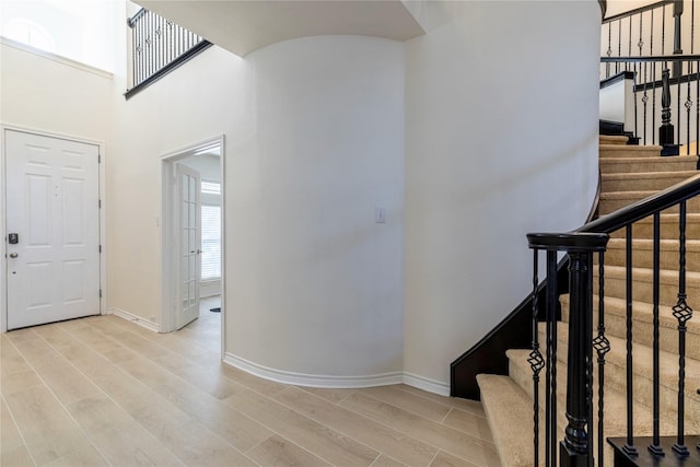 entrance foyer with light wood-style floors, stairway, and baseboards