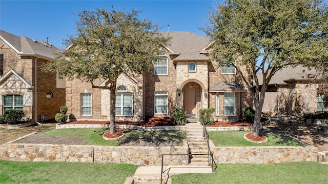 french provincial home with brick siding, a front lawn, and a shingled roof