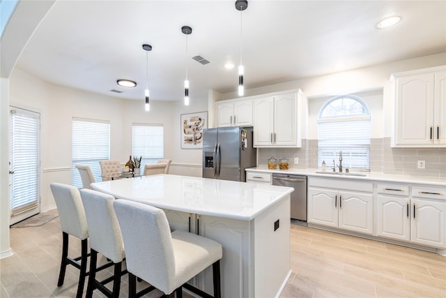 kitchen featuring appliances with stainless steel finishes, a sink, a kitchen island, plenty of natural light, and recessed lighting