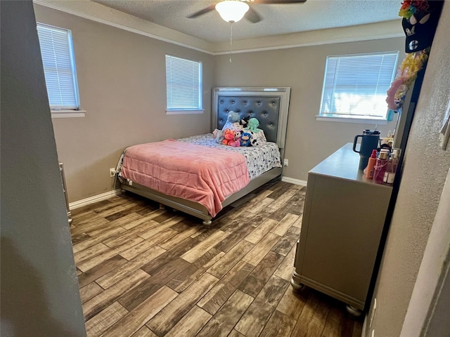 bedroom featuring ornamental molding, a ceiling fan, a textured ceiling, wood finished floors, and baseboards