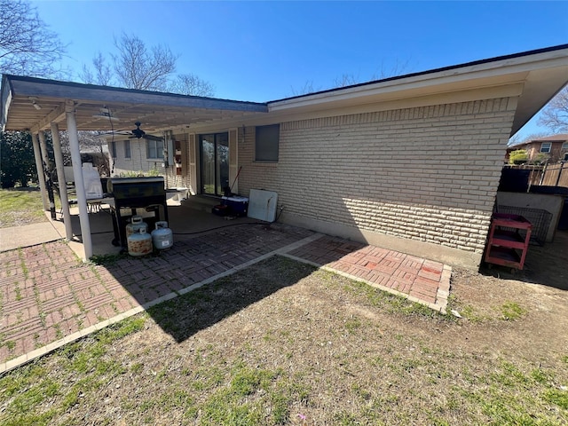 rear view of property with ceiling fan, a patio, and brick siding