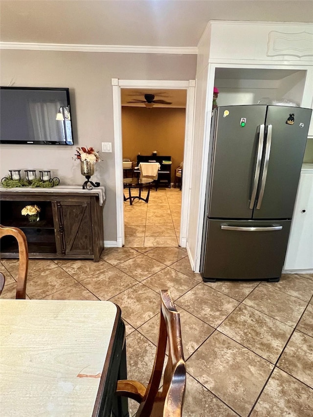 kitchen with light tile patterned floors, ornamental molding, freestanding refrigerator, and baseboards