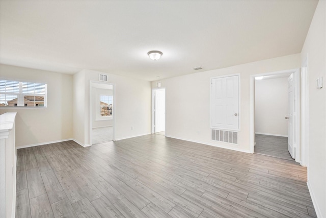 unfurnished living room with baseboards, visible vents, and light wood finished floors