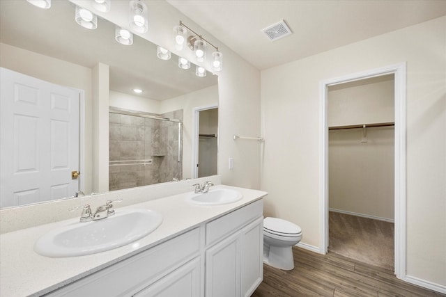 full bath featuring a shower stall, visible vents, a walk in closet, and a sink