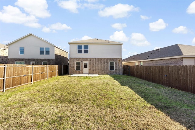 back of property featuring a yard, brick siding, a patio area, and a fenced backyard