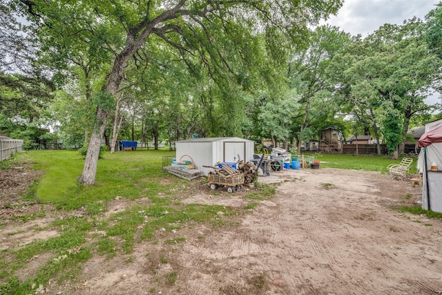 view of yard featuring fence, a storage unit, and an outbuilding