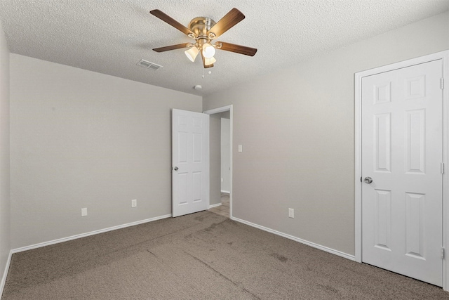 unfurnished bedroom featuring a textured ceiling, carpet, visible vents, and baseboards