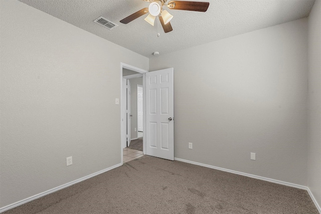 carpeted spare room featuring baseboards, visible vents, and a textured ceiling