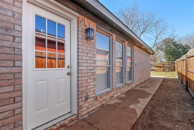 property entrance featuring fence and brick siding