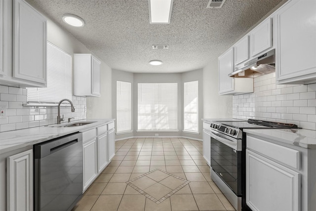 kitchen featuring light tile patterned floors, under cabinet range hood, stainless steel appliances, a sink, and visible vents