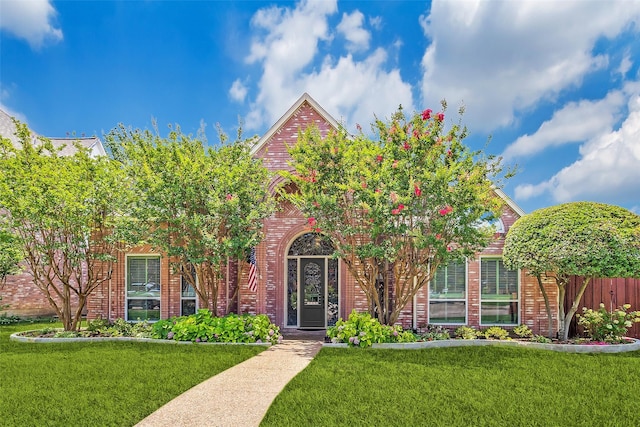 view of property hidden behind natural elements featuring a front yard and brick siding